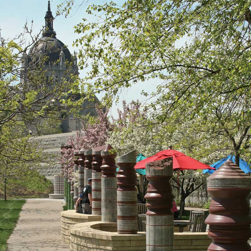 Rounded beams stand in a line with the St. Paul Cathedral in the background. Brooks Family Courtyard.