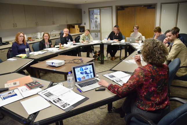 Group of 7 or 8 individuals in meeting sitting at an oval table.